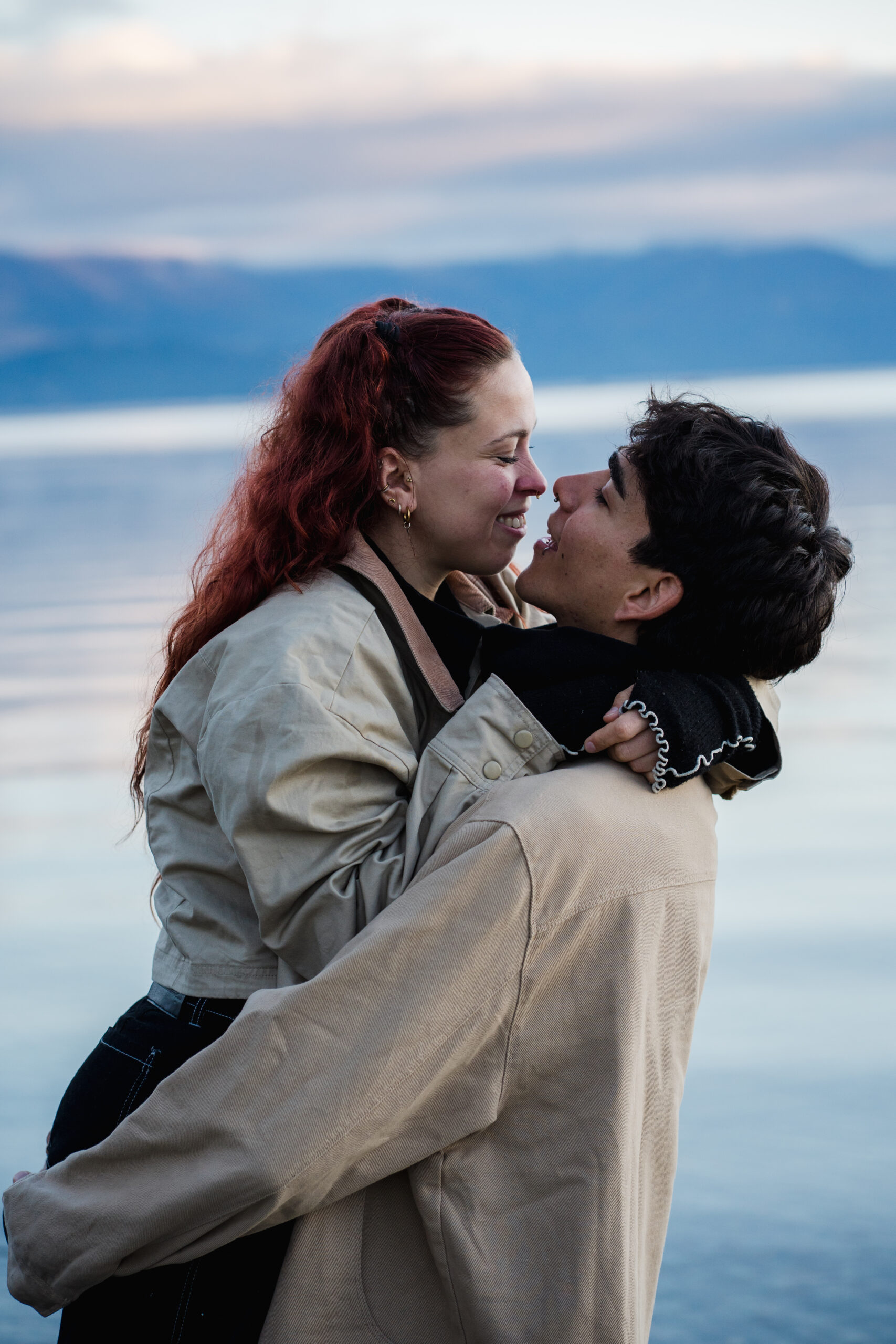 Marcos lifting Suyii at the edge of Lake Wanaka as they look into each other's eyes during their couples photoshoot
